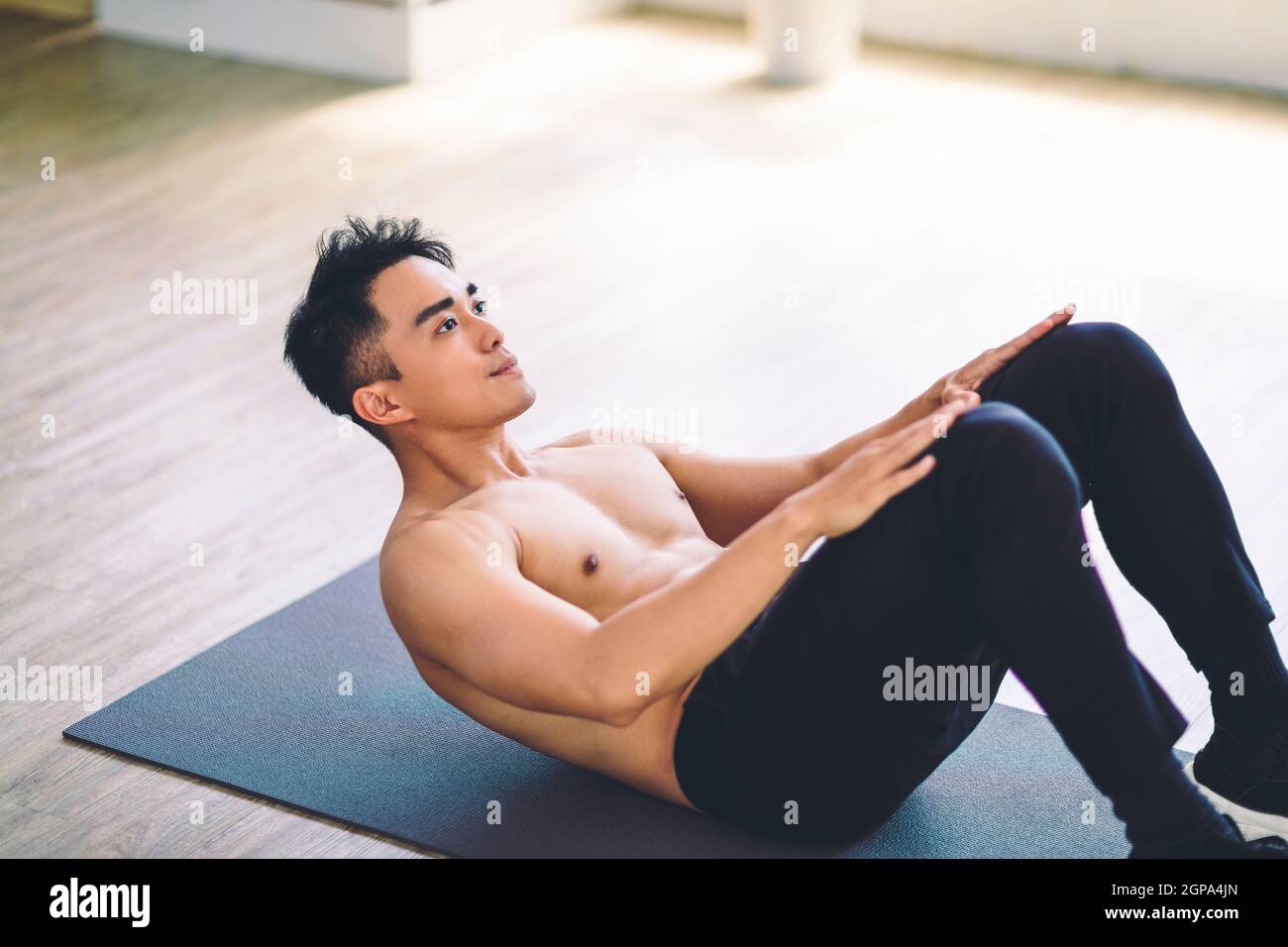 Muskulösen asiatischen jungen Mann tun Übungen auf dem Boden zu Hause Stockfoto