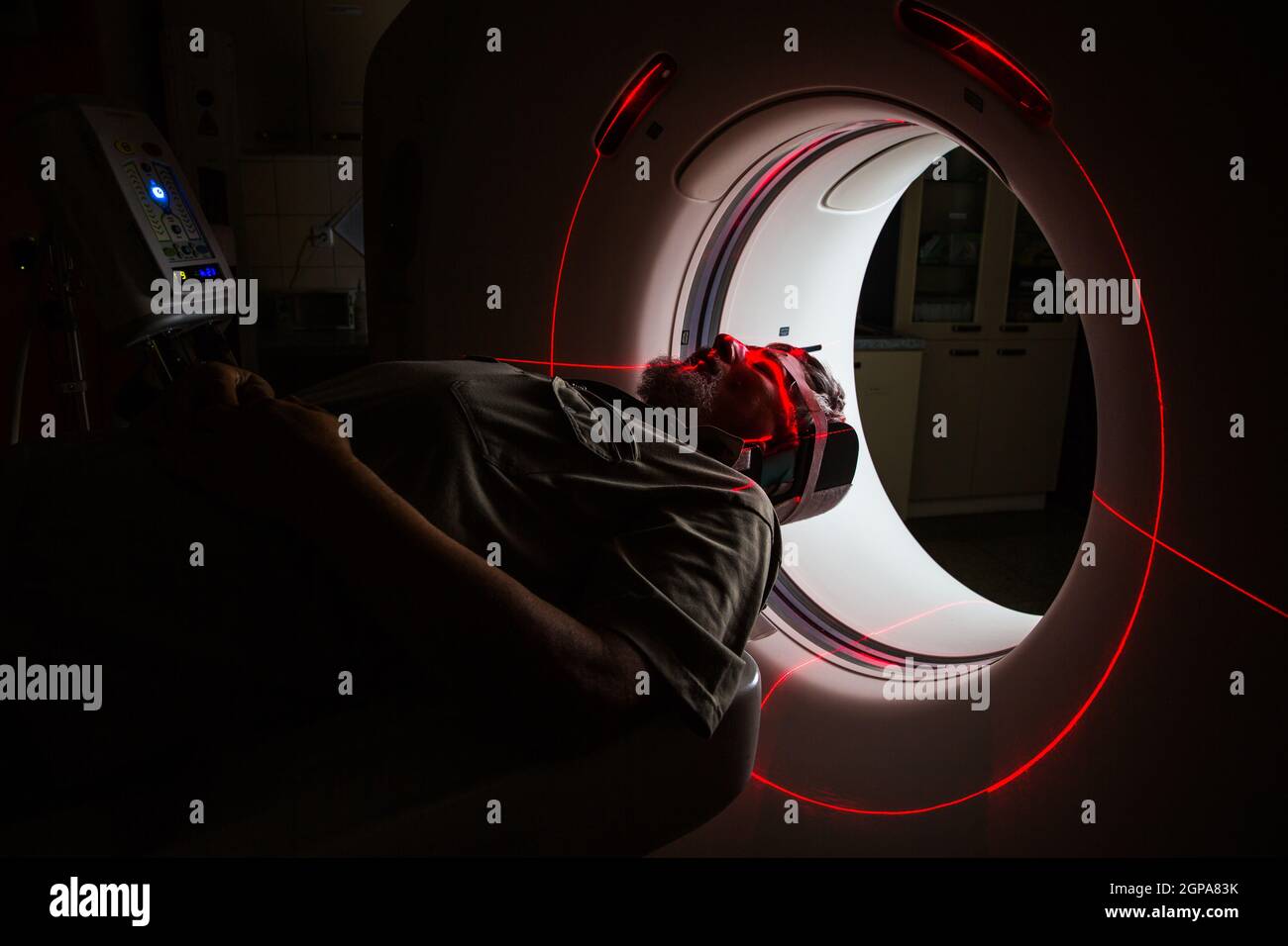 Leitender Mann, der in einem modernen Krankenhaus einen Computerized Axial Tomography (CAT) Scan medizinischen Test/Untersuchung durchläuft (farbiges Bild; flacher Freiheitsgrad) Stockfoto