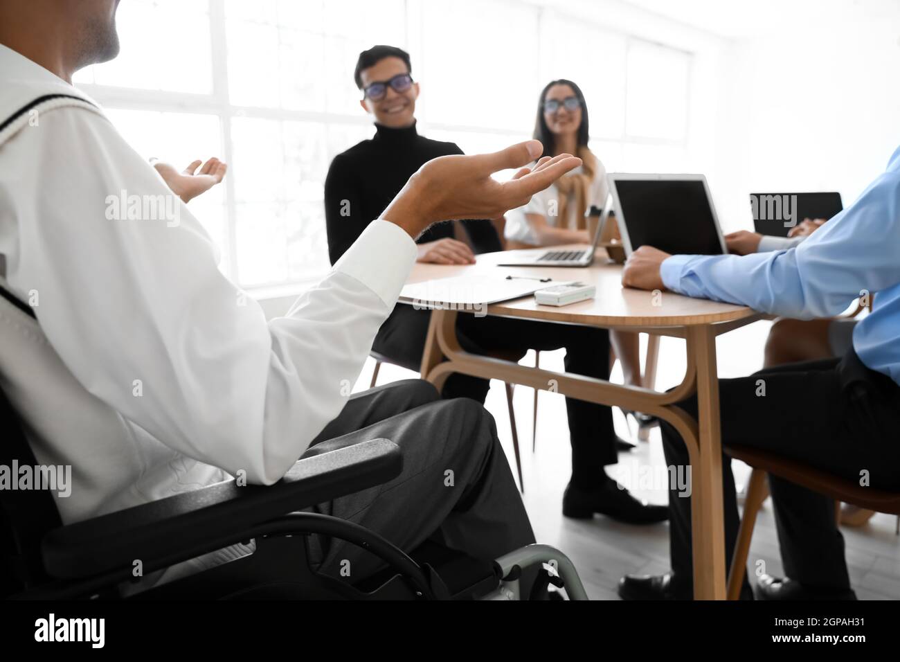 Mann im Rollstuhl, der im Büro vorgeführt wird Stockfoto