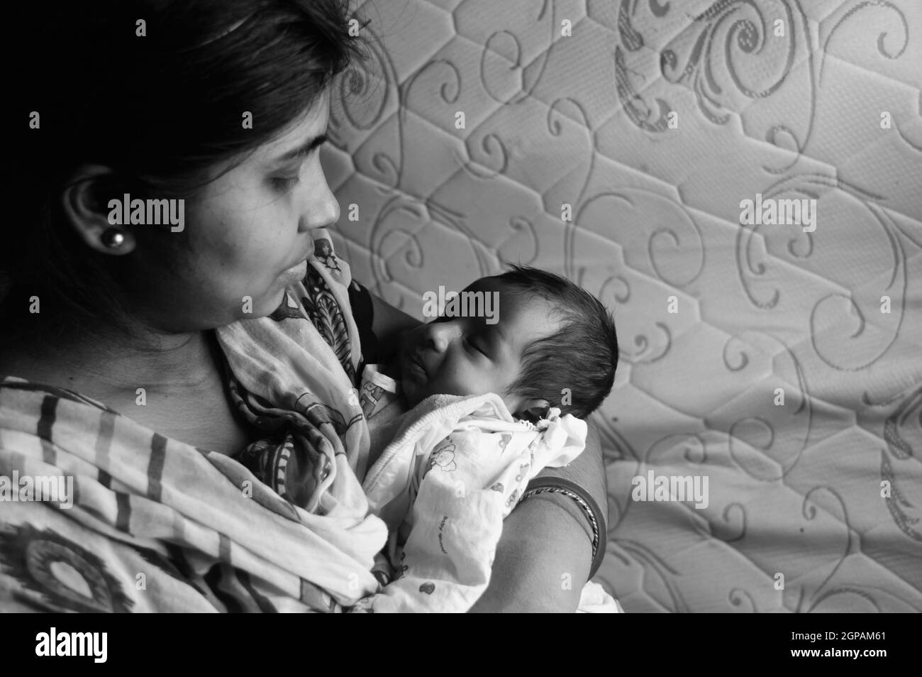 Nahaufnahme Gesicht eines niedlichen neugeborenen Jungen schaut glücklich auf seine Mutter in ihrer Mutter Schoß. Ein Monat altes süßes kleines Kleinkind Kleinkind. Indische Ethnie. F Stockfoto