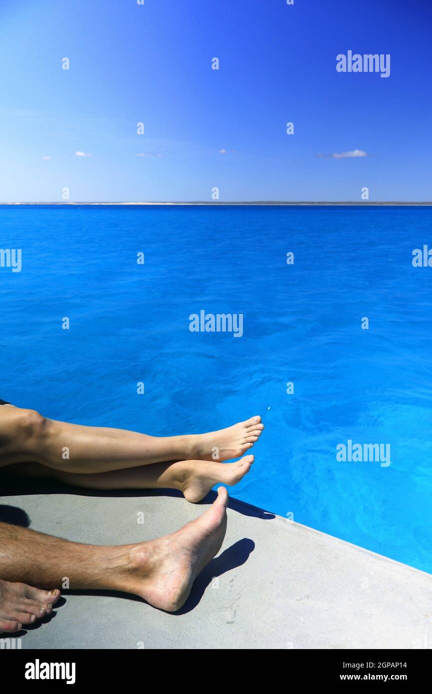 Die Beine eines Paares entspannen sich auf dem Sonnendeck des Bootes, der Lagune des Ningaloo Reef Marine Park, Westaustralien. Nein, MR Stockfoto
