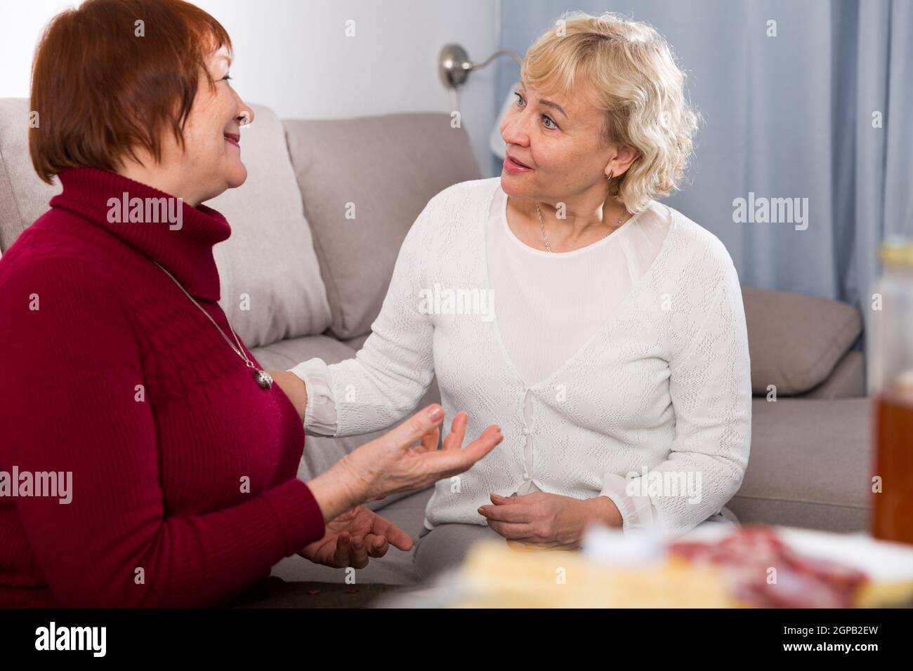 Zwei ältere Damen im Gespräch auf dem Sofa Stockfoto