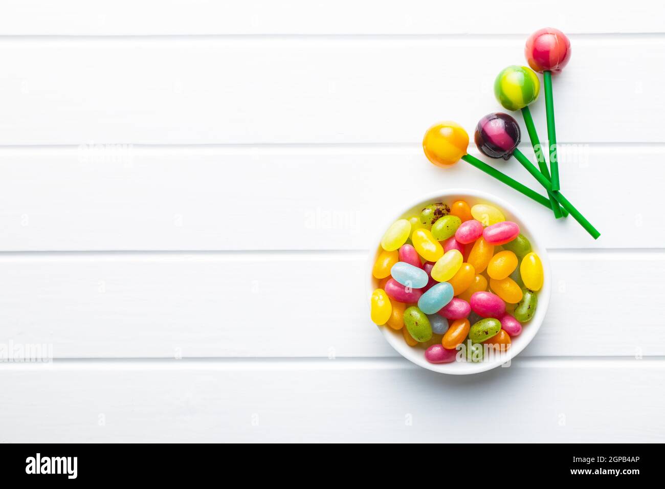 Süße, fruchtige Lutscher und Jelly Beans auf weißem Tisch. Draufsicht. Stockfoto