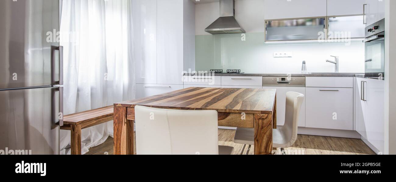 Moderne Küche Interior Design Architektur Stock Image, Foto von einer modernen weißen Küche mit einem dunklen Holztisch, High-End-Geräte und viel Tageslicht Stockfoto