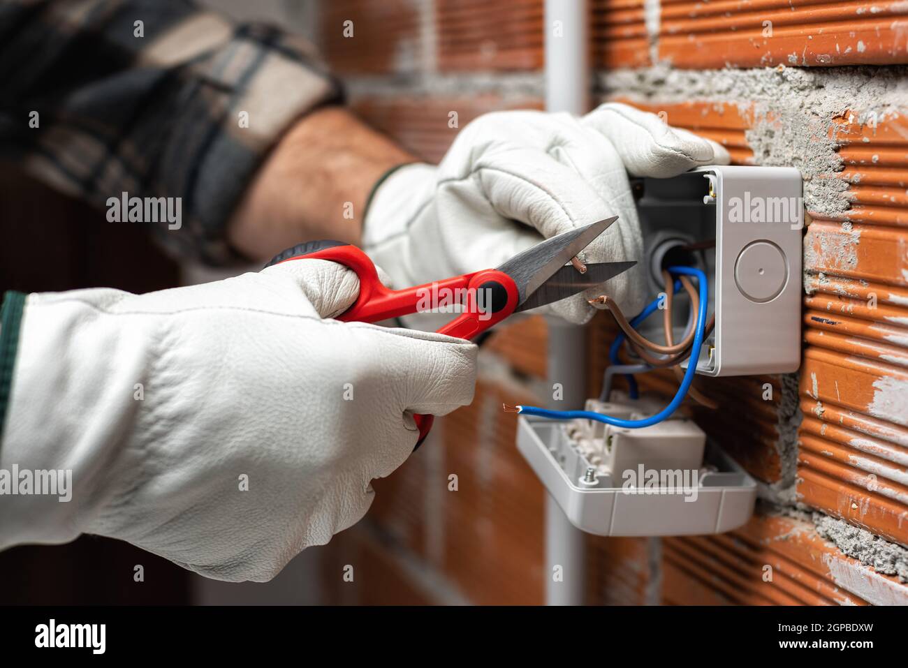 Der Elektriker Arbeiter bei der Arbeit mit der Schere bereitet die elektrischen Kabel des häuslichen elektrischen Systems vor. Bauindustrie. Stockfoto