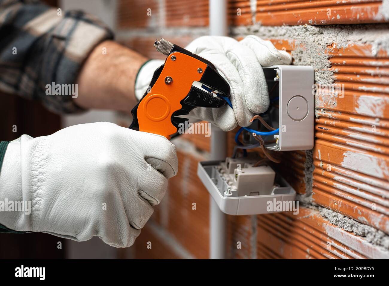 Elektriker Arbeiter bei der Arbeit mit Abisolierer bereitet die elektrischen Kabel der häuslichen elektrischen Anlage. Bauindustrie. Stockfoto