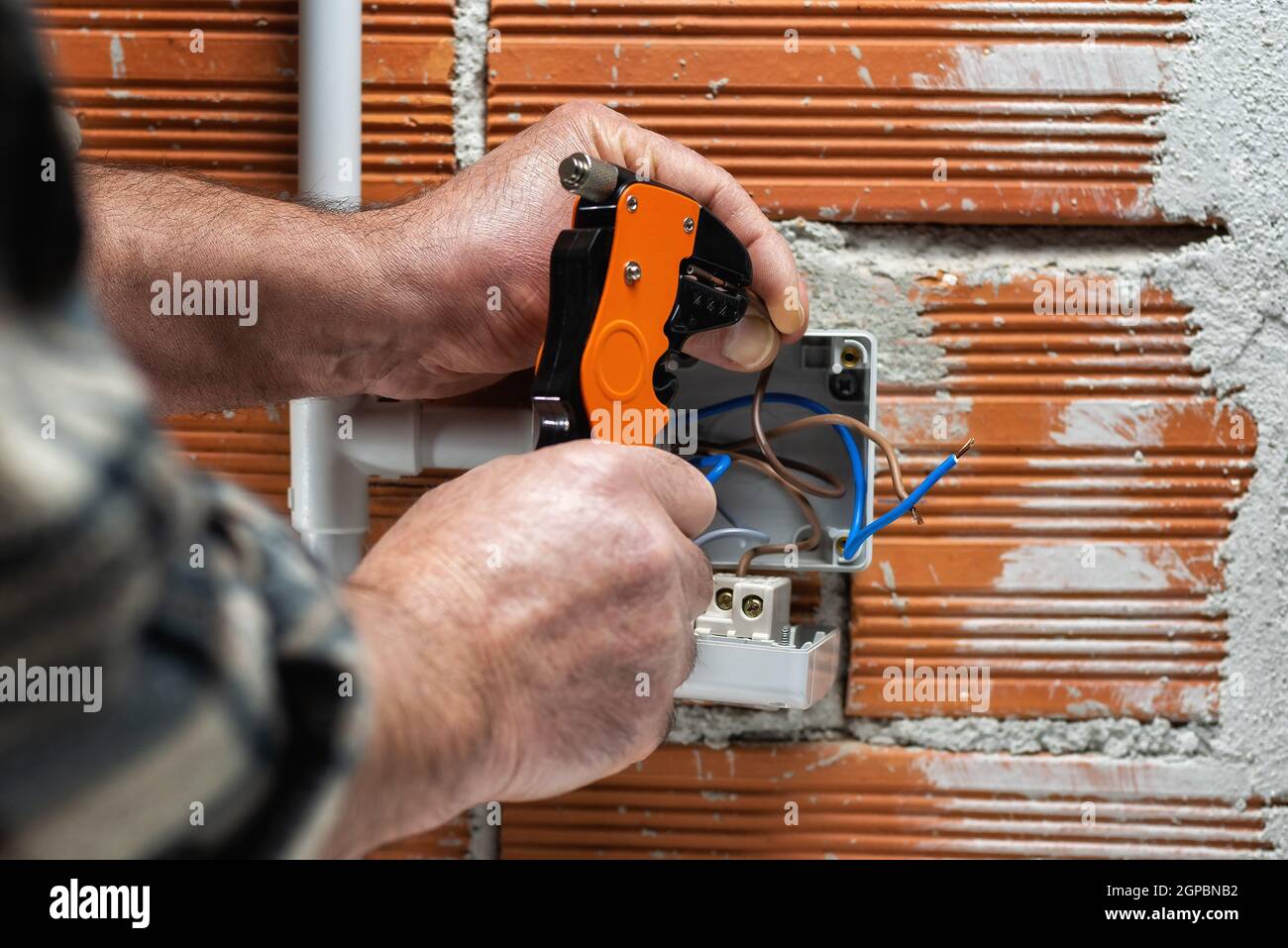 Elektriker Arbeiter bei der Arbeit mit Abisolierer bereitet die elektrischen Kabel der häuslichen elektrischen Anlage. Bauindustrie. Stockfoto