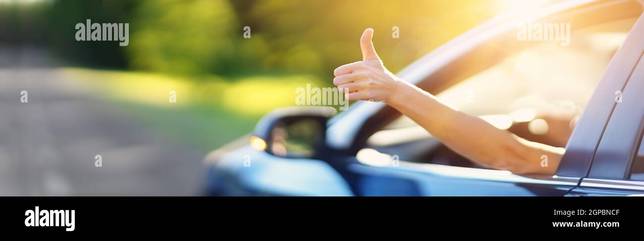 Frau in ihrem Auto gestikulieren den Daumen nach oben. Konzept des Autokaufens und positive Emotionen. Stockfoto