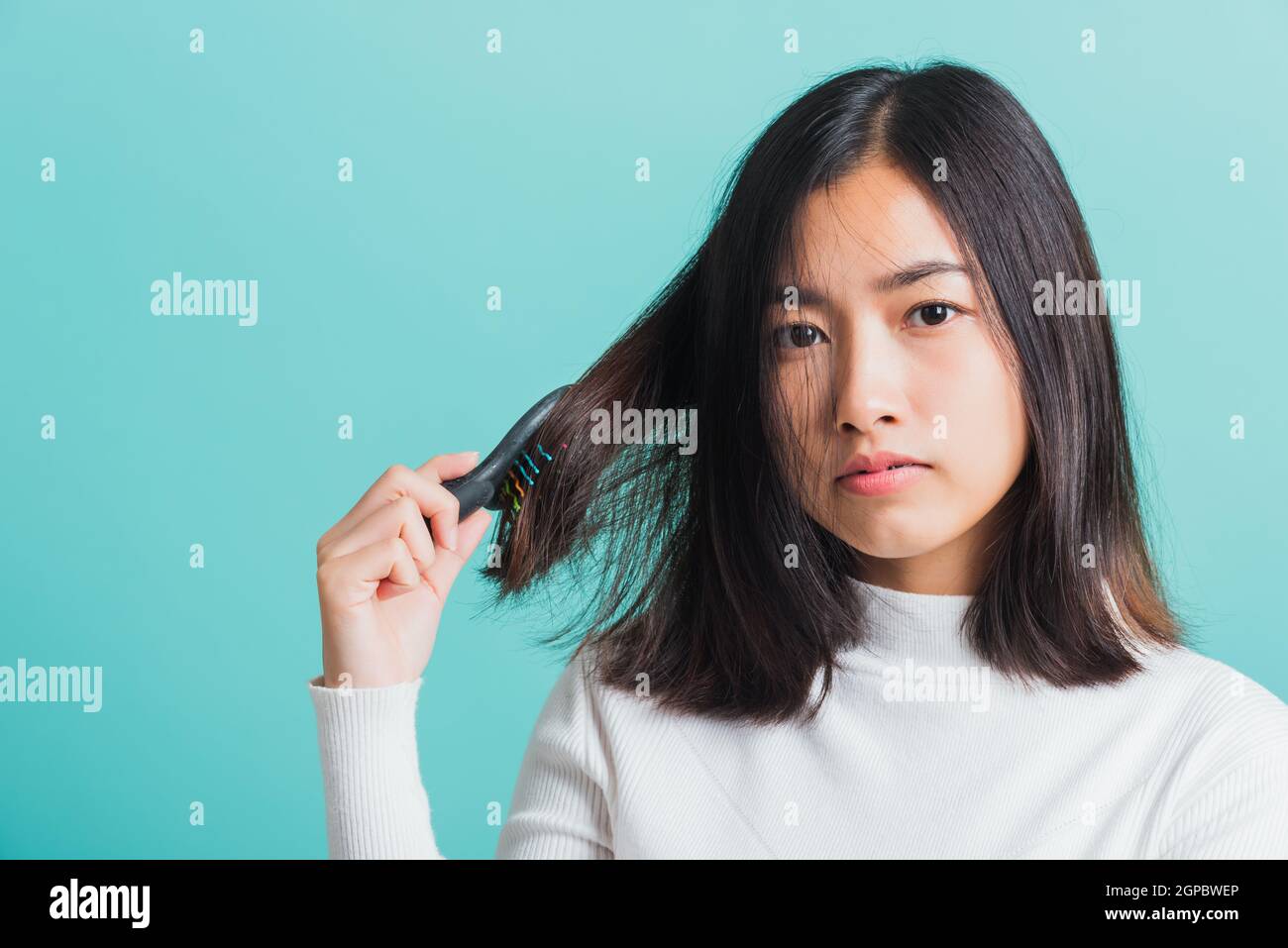 Junge schöne asiatische Frau aufgeregt mit einem Kamm und Problem Haar, Porträt weiblich schockiert leiden an Haarausfall Problem, Studio erschossen auf einem BL isoliert Stockfoto