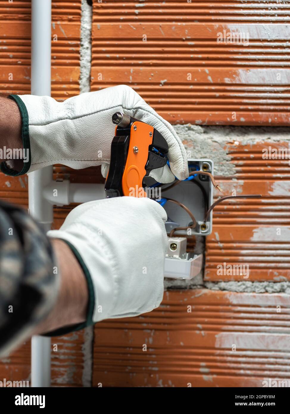Elektriker Arbeiter bei der Arbeit mit Abisolierer bereitet die elektrischen Kabel der häuslichen elektrischen Anlage. Sicheres Arbeiten mit Schutzhandschuhen. Co Stockfoto