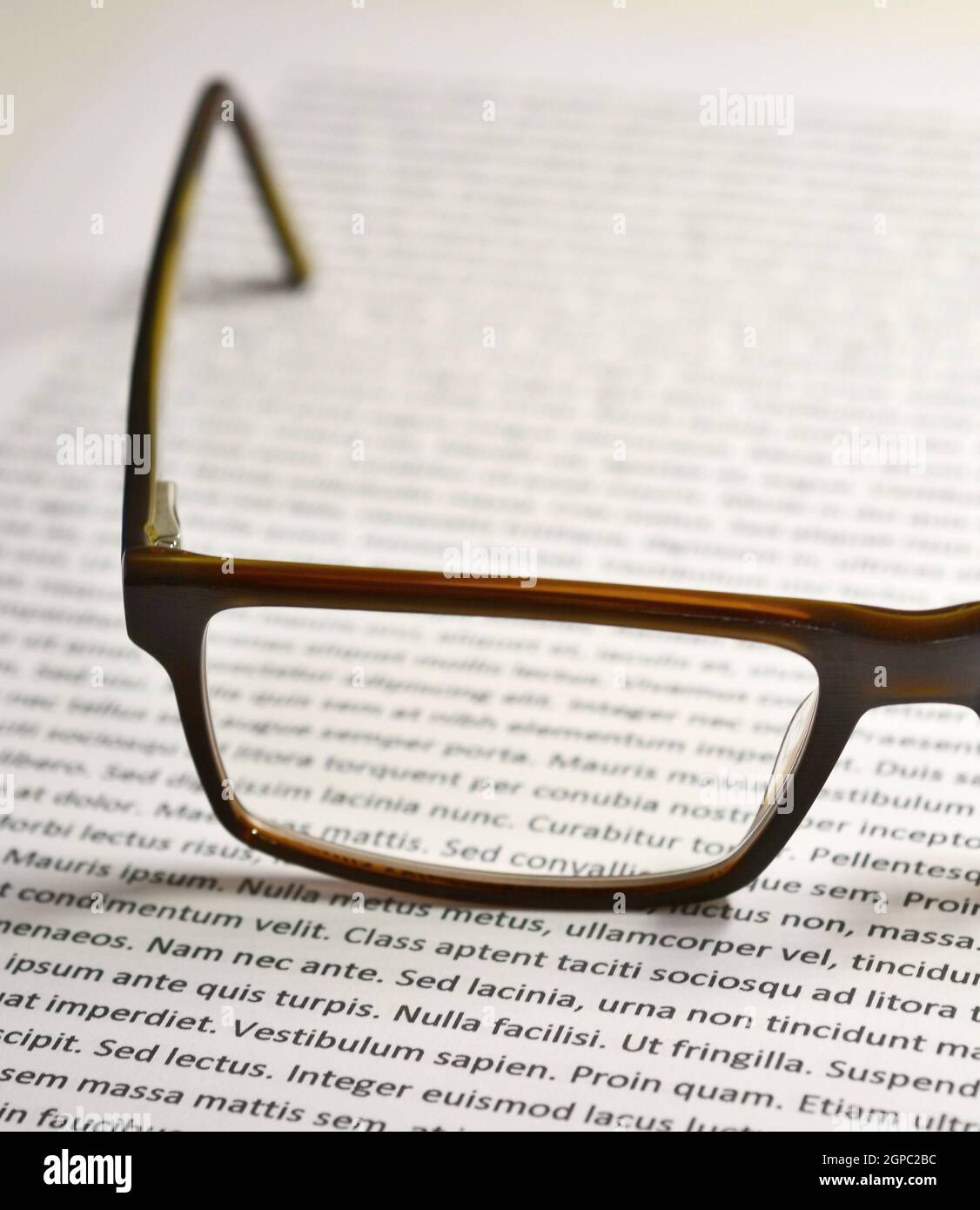 Nahaufnahme der Brille auf Papierblatt mit lorem ipsum-Text. Stockfoto