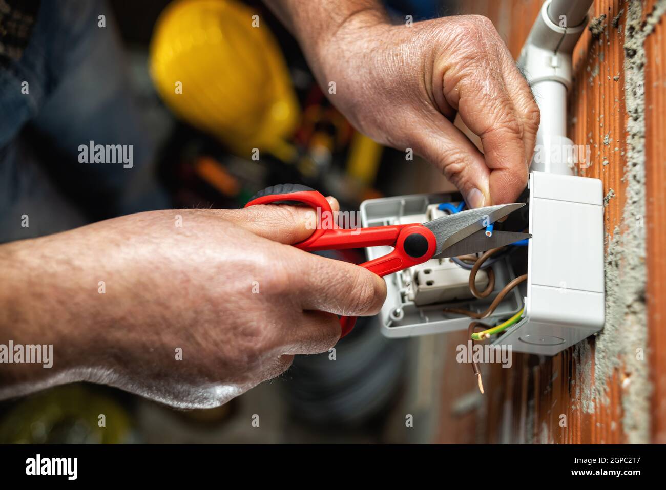 Blick von oben. Der Elektriker Arbeiter bei der Arbeit mit der Schere bereitet die elektrischen Kabel des häuslichen elektrischen Systems vor. Bauindustrie. Stockfoto