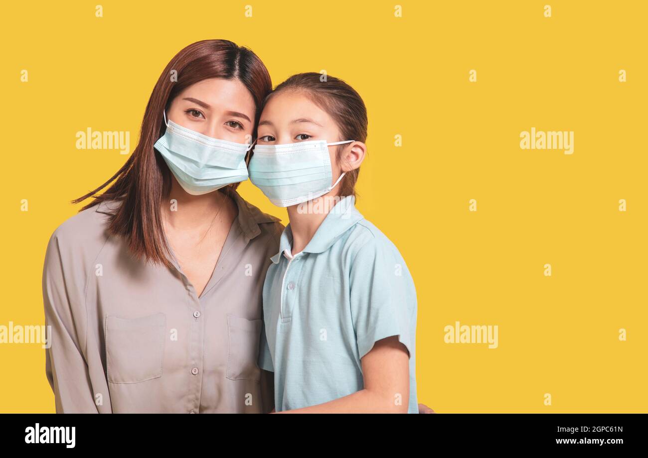 Mutter umarmt kleine Tochter in schützende medizinische Masken während Covid-19 Pandemien Stockfoto