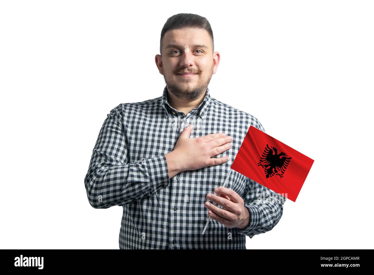 Weißer Kerl hält eine Fahne von Albanien und hält seine Hand auf seinem Herzen isoliert auf einem weißen Hintergrund mit Liebe zu Albanien. Stockfoto