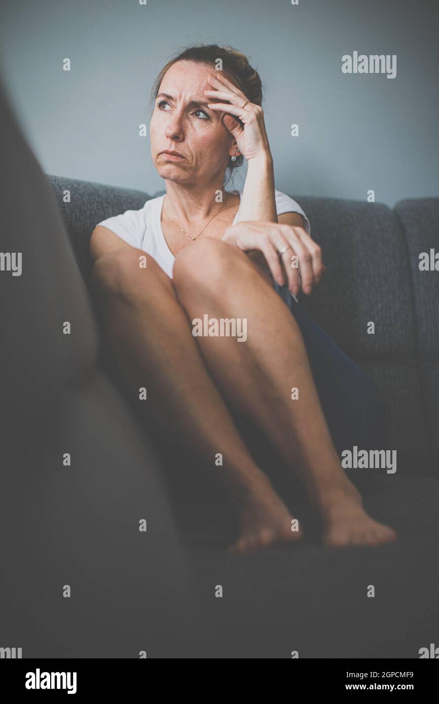 Deprimierte Frau mittleren Alters zu Hause fühlt sich traurig, einsam, ängstlich (farbiges Bild) Stockfoto