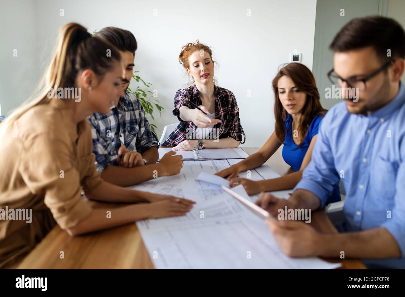 Glückliche, multiethnische Gruppe von Geschäftsleuten, die gemeinsam an einem Treffen im Büro arbeiten Stockfoto