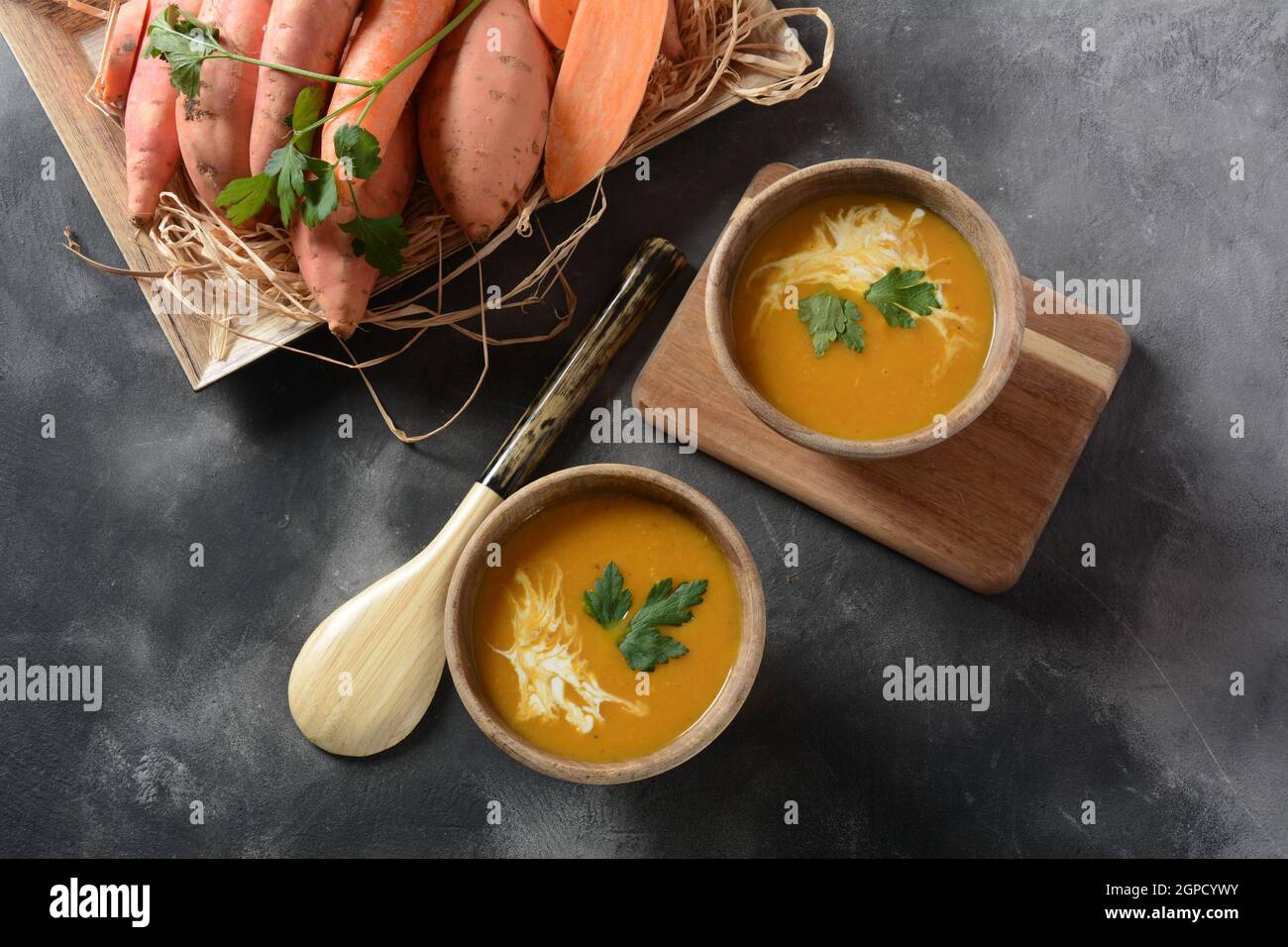 Süßkartoffel- und Karottensuppe mit Sauerrahm in Holzschüssel serviert ...