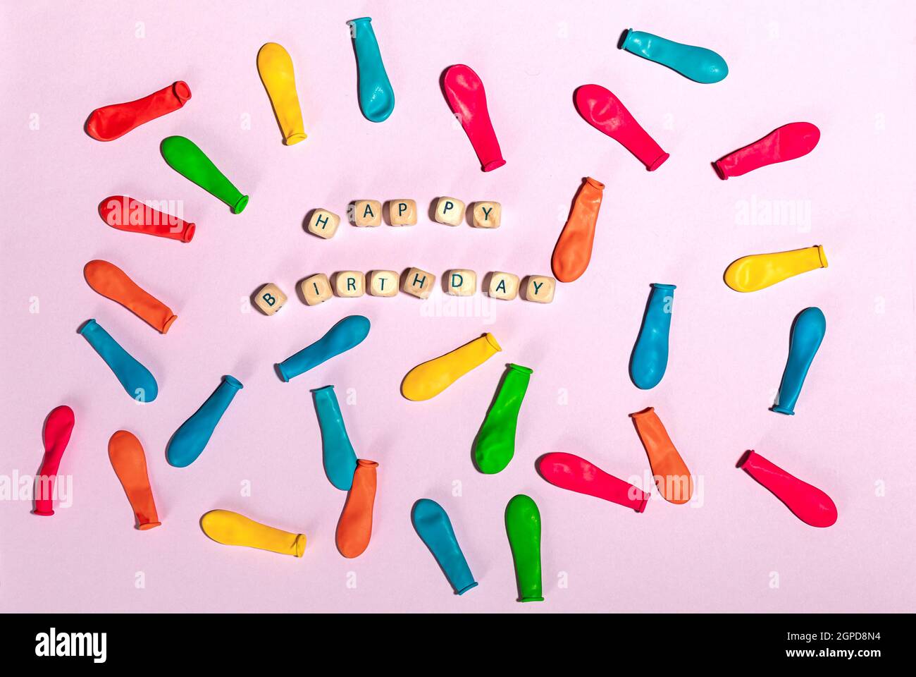Flach legen mit bunten Luftballons und Holzziegel mit Text Happy Birthday auf rosa Hintergrund. Stockfoto