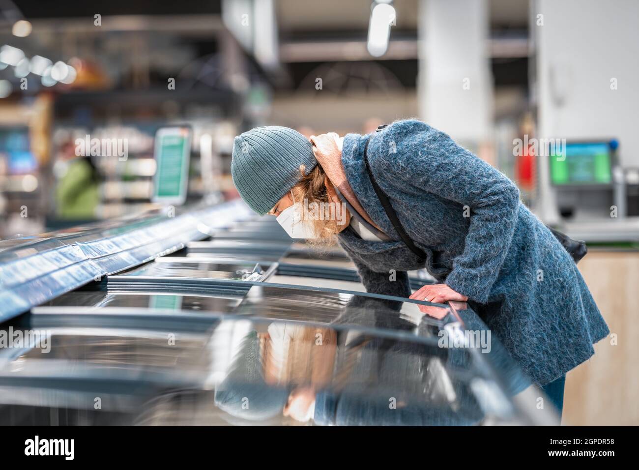Die Frau im Laden wählt Lebensmittel aus dem Gefrierschrank Stockfoto