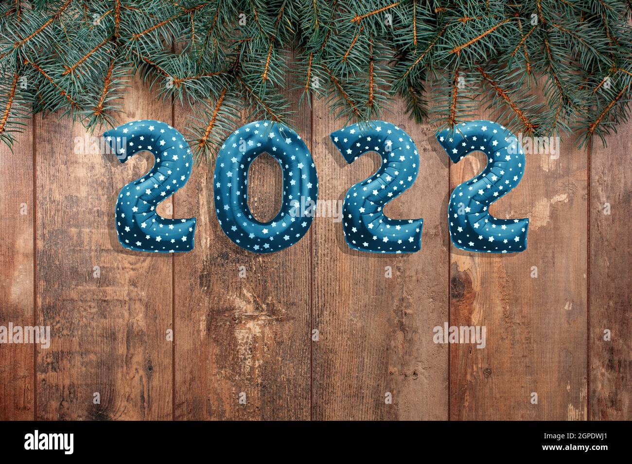 Frohes Neues Jahr 2022. Folienballons Zahlen 2022 auf Holz rustikalen Tisch mit Zweigen von Weihnachtsbäumen. Frohes neues Jahr 2022 Feier. Flach legen, bis Stockfoto