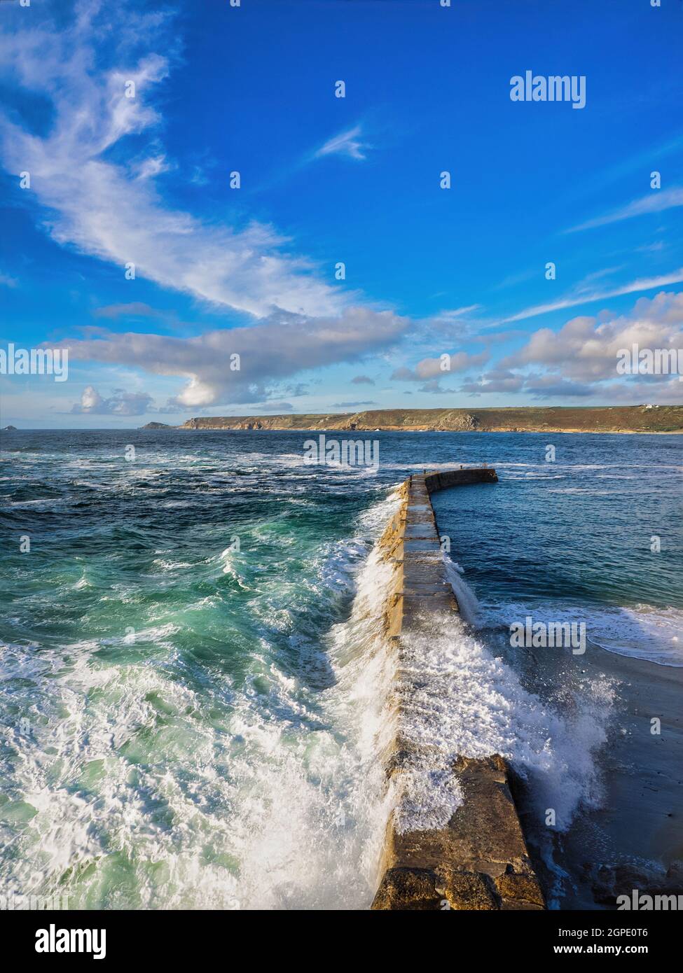 Weiße Kappen und Wellen stürzen über die Hafenmauer von Sennen Cove in Cornwall. Stockfoto
