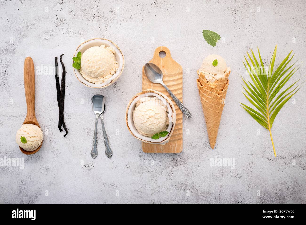 Kokoseis Aromen in der Hälfte der Kokosnuss Setup auf weißem Stein Hintergrund. Sommer und Süße Menükonzept. Stockfoto