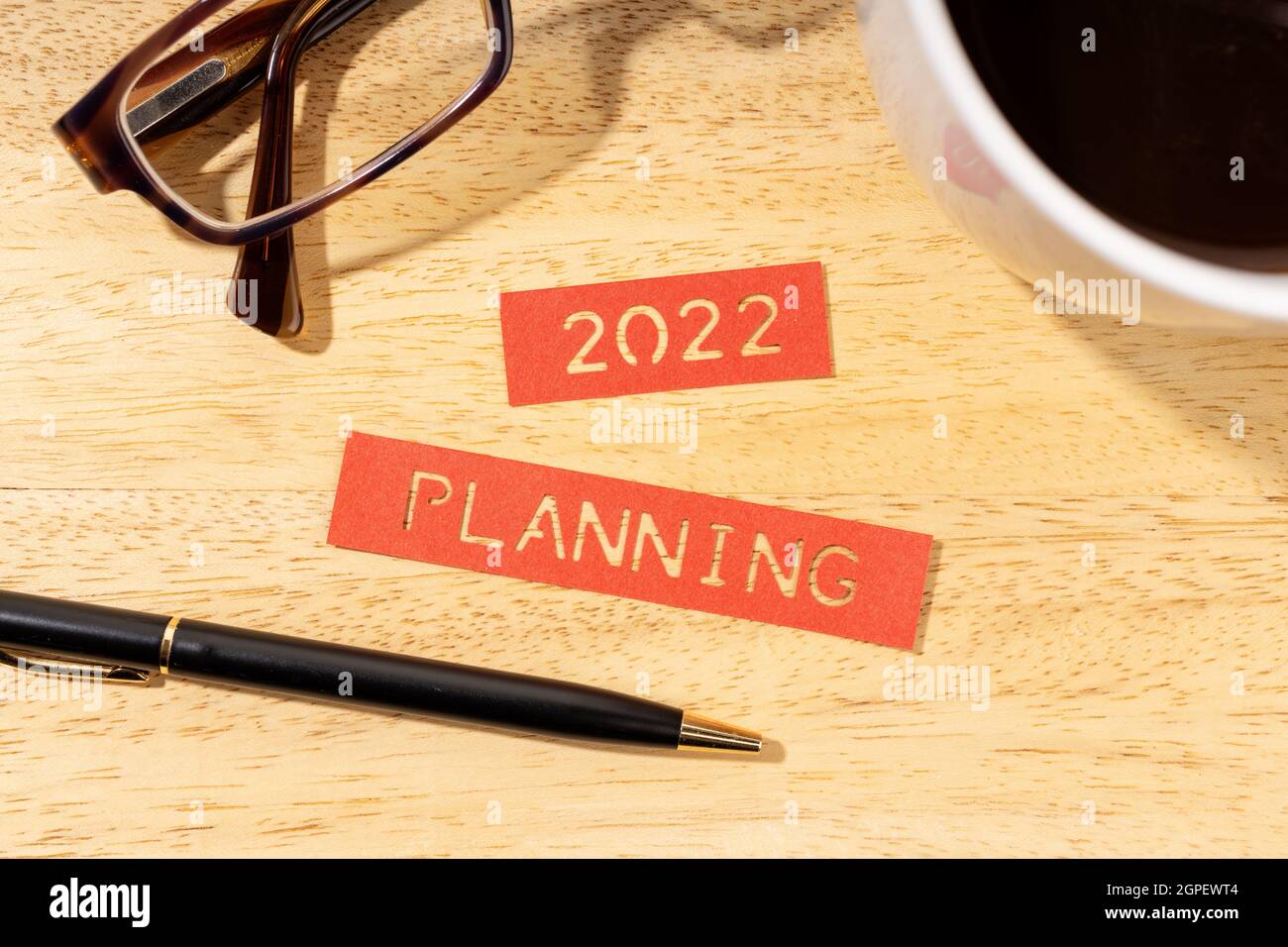 Planungskonzept für das neue Jahr 2022. Etiketten, Stift, Tasse Kaffee und Brillen auf Holzschreibtisch Stockfoto