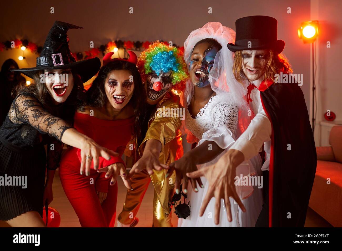 Eine Gruppe junger Freunde in gruseligen Kostümen, die zusammen Spaß auf der Halloween Party haben Stockfoto