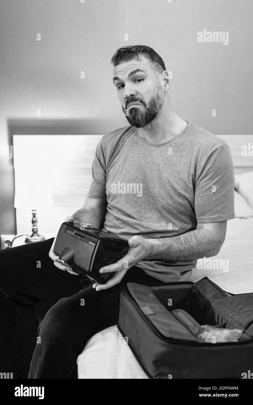 Reifer glücklicher Mann mit chronischen Atemproblemen erwägt die Verwendung CPAP-Maschine auf dem Bett im Schlafzimmer sitzen. Gesundheitswesen, CPAP, Schnarchen Konzept Stockfoto