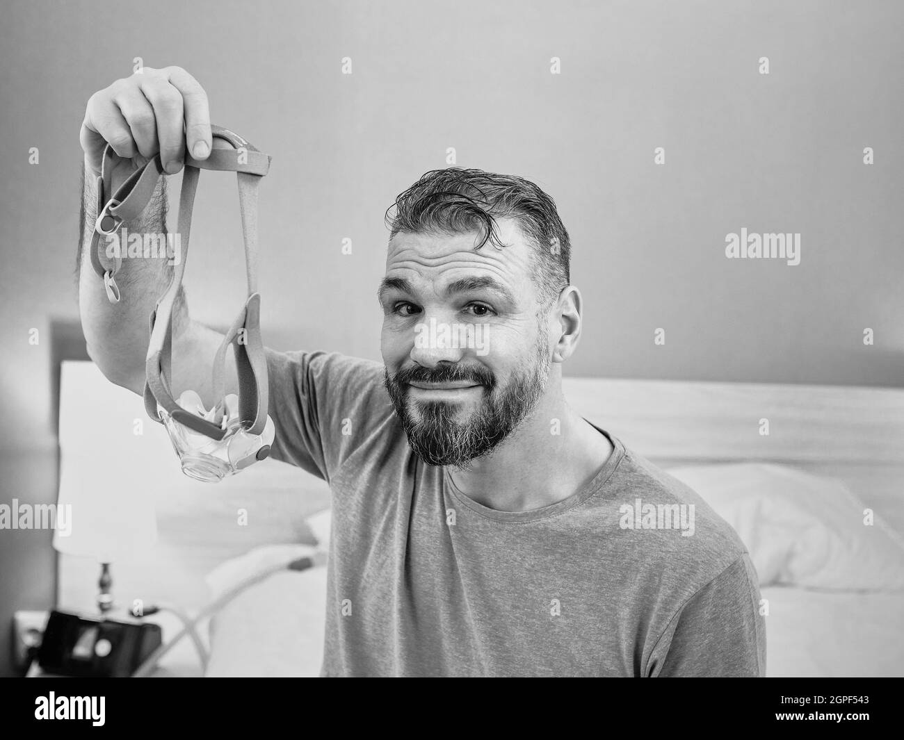 Reifer glücklicher Mann mit chronischen Atemproblemen erwägt die Verwendung CPAP-Maschine auf dem Bett im Schlafzimmer sitzen. Gesundheitswesen, CPAP, Schnarchen Konzept Stockfoto