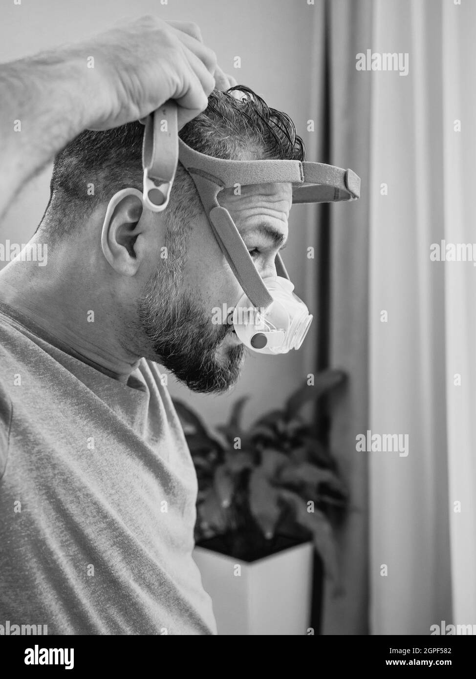 Unglücklich schockiert Mann mit chronischen Atemproblemen überrascht, indem CPAP-Maschine auf dem Bett im Schlafzimmer sitzen. Stockfoto