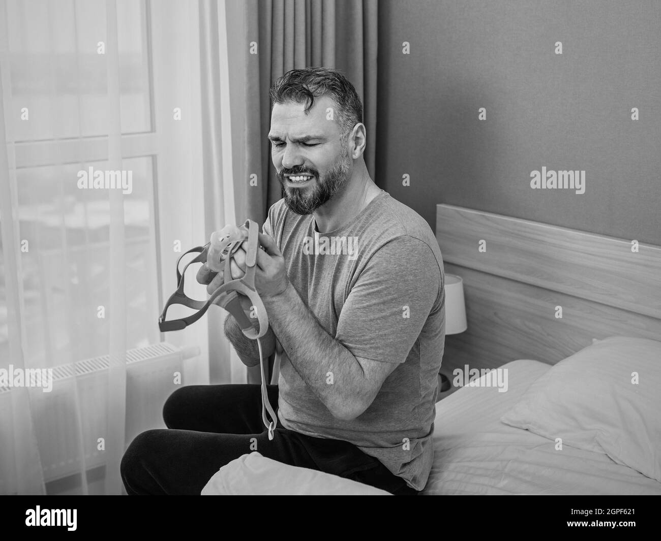 Reifer glücklicher Mann mit chronischen Atemproblemen erwägt die Verwendung CPAP-Maschine auf dem Bett im Schlafzimmer sitzen. Gesundheitswesen, CPAP, Schnarchen Konzept Stockfoto