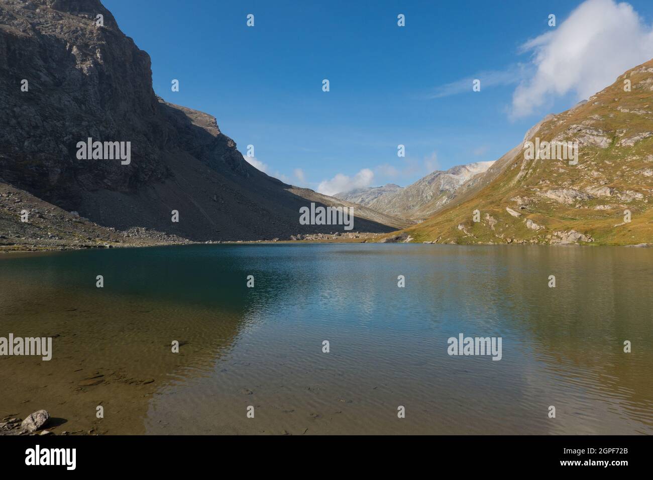 Bergsee, Berge, die sich in spiegelglattem Wasser spiegeln, steile Felsen und alpine Wiese Stockfoto