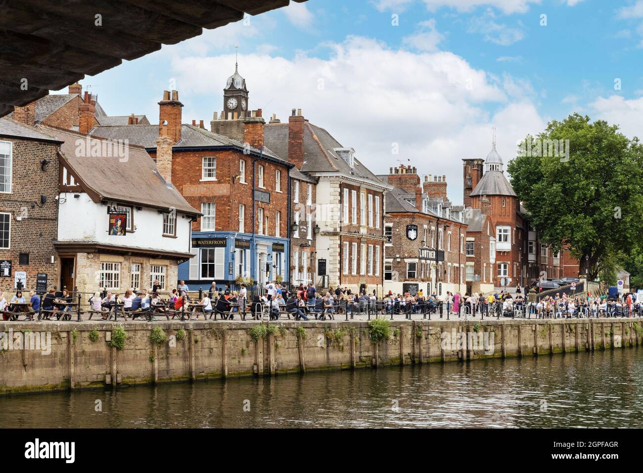 River Ouse York UK; Menschen säumen das Flussufer im Sommer vor Pubs; The River Ouse, York City Centre, York, Yorkshire UK Stockfoto