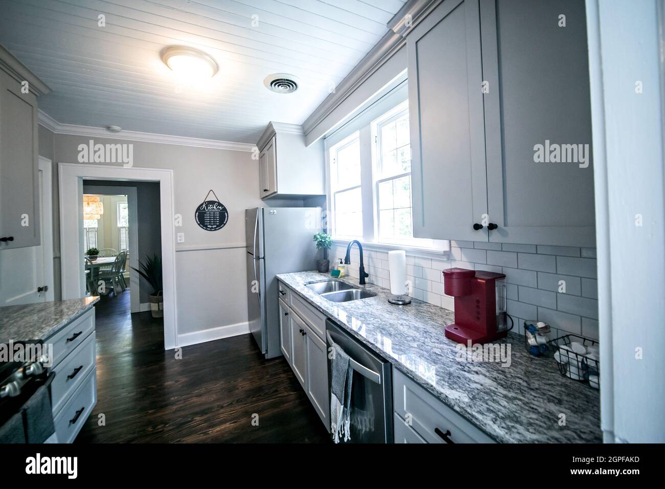 Eine kleine Cottage-Küche mit grauen Schränken und dunklen Hartholzböden in einem kurzfristigen Miethaus Stockfoto