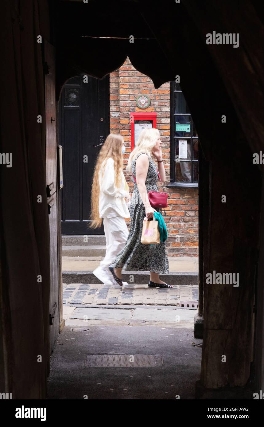 The Shambles York England – Frauen, die in einem Bogen auf der Straße im mittelalterlichen Shambles-Viertel im Zentrum von York, Großbritannien, vorbeigehen Stockfoto