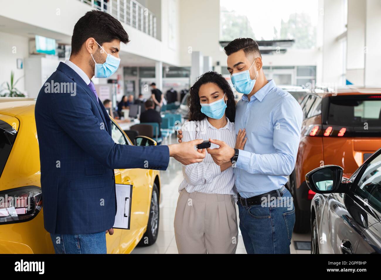 Arabisches Paar in Gesichtsmasken beim Kauf eines neuen Autos im Ausstellungsraum Stockfoto