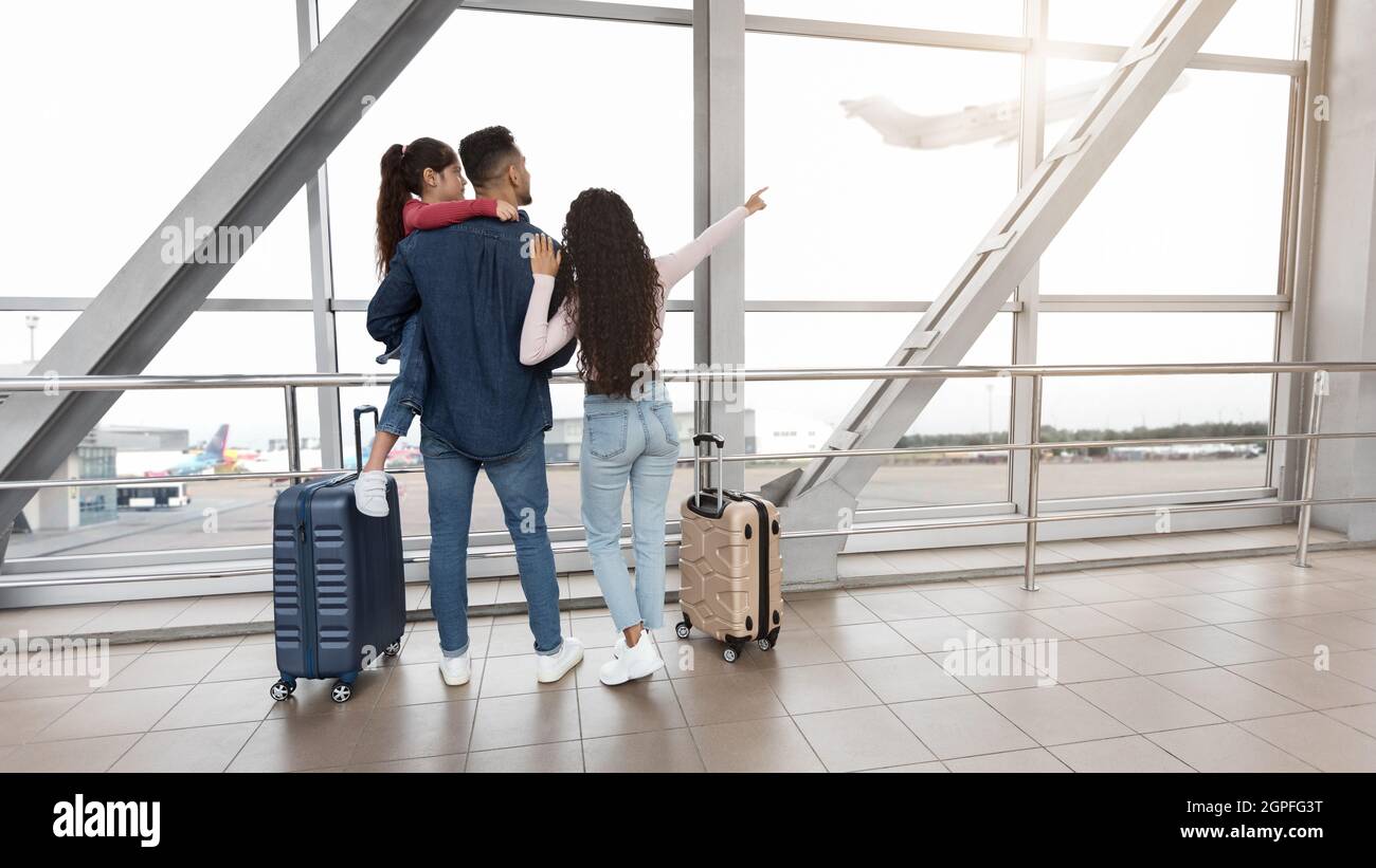 Familienreisen. Eltern Mit Kleiner Tochter Stehen Am Flughafenterminal, Rückansicht Stockfoto