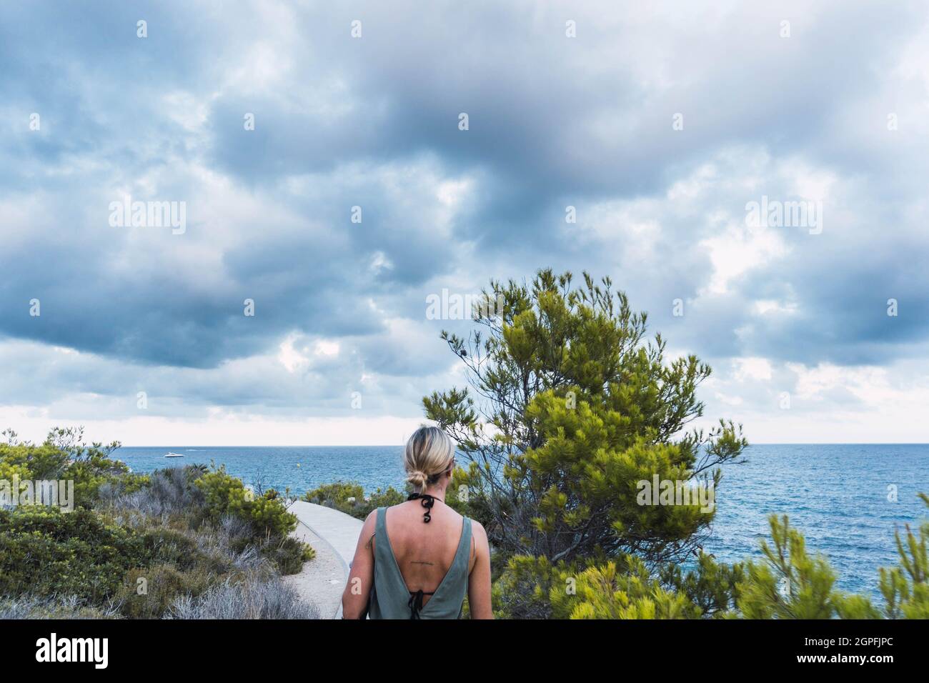 Person, die in einer Meereslandschaft mit Bäumen und bewölktem Himmel steht Stockfoto