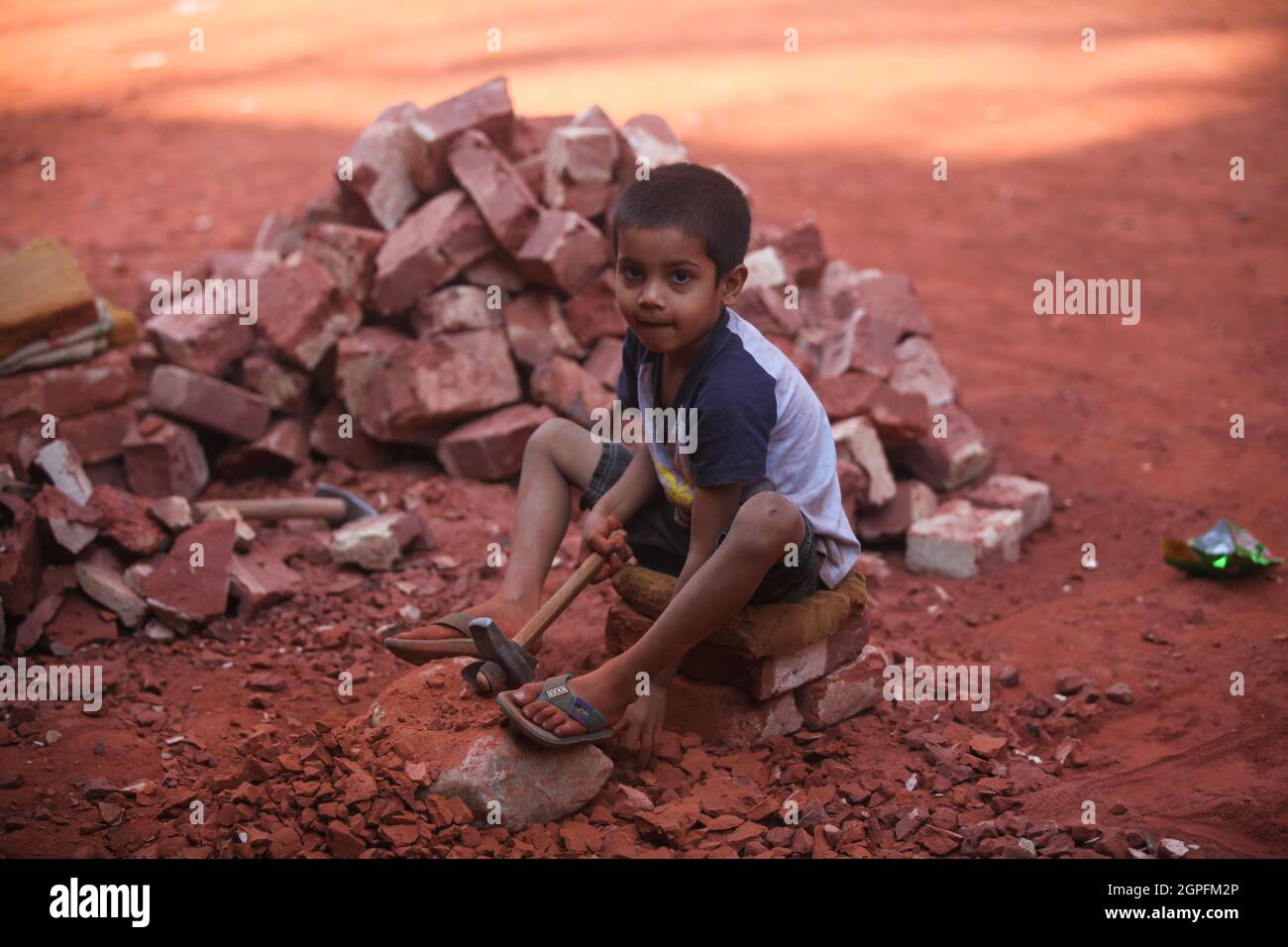 Eine bangladeschische Kinderarbeit schaut während der Pause auf die Kamera, die in einem Backsteinhof im Turag-Fluss im Bereich Aminbazar in Dhaka auf Marc arbeitet Stockfoto