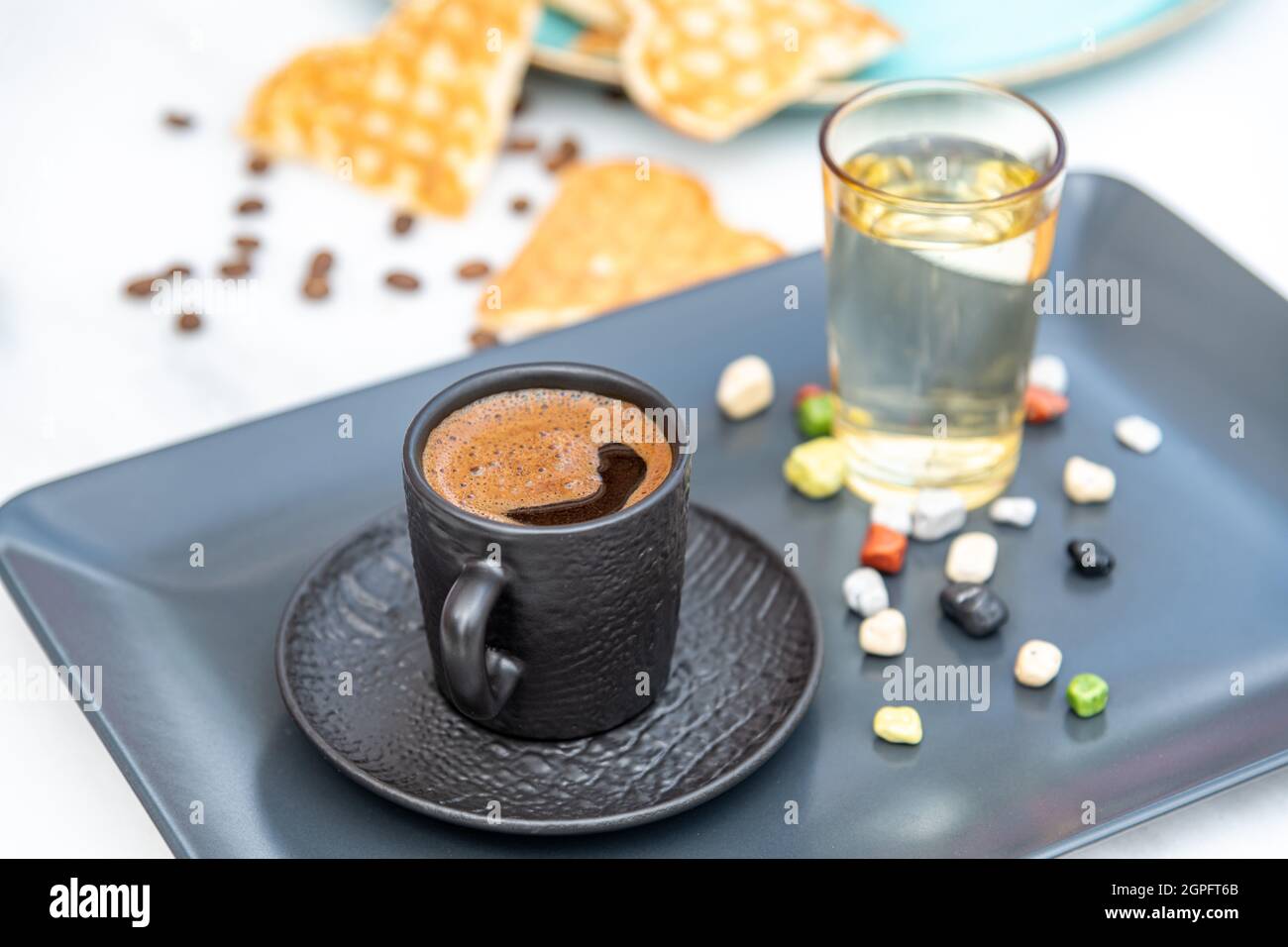 Traditioneller türkischer Kaffee in einer modernen schwarzen Tasse mit Wasser und Zucker. Selektiver Fokus Stockfoto