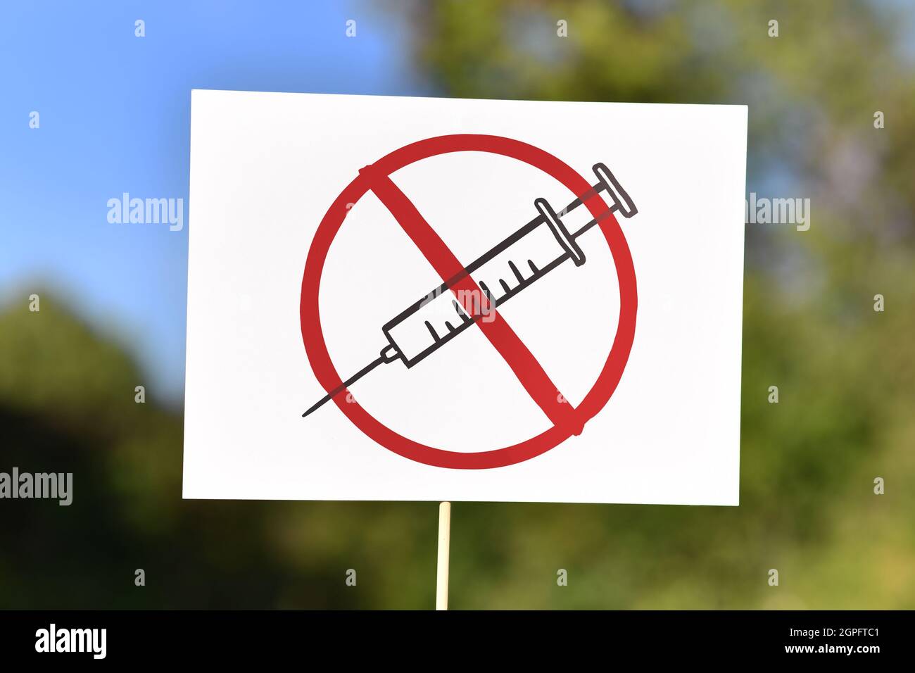 Anti-Impfstoff-Demonstrationsschild mit Spritzenzeichnung in rot durchgestrichenen Kreis Stockfoto