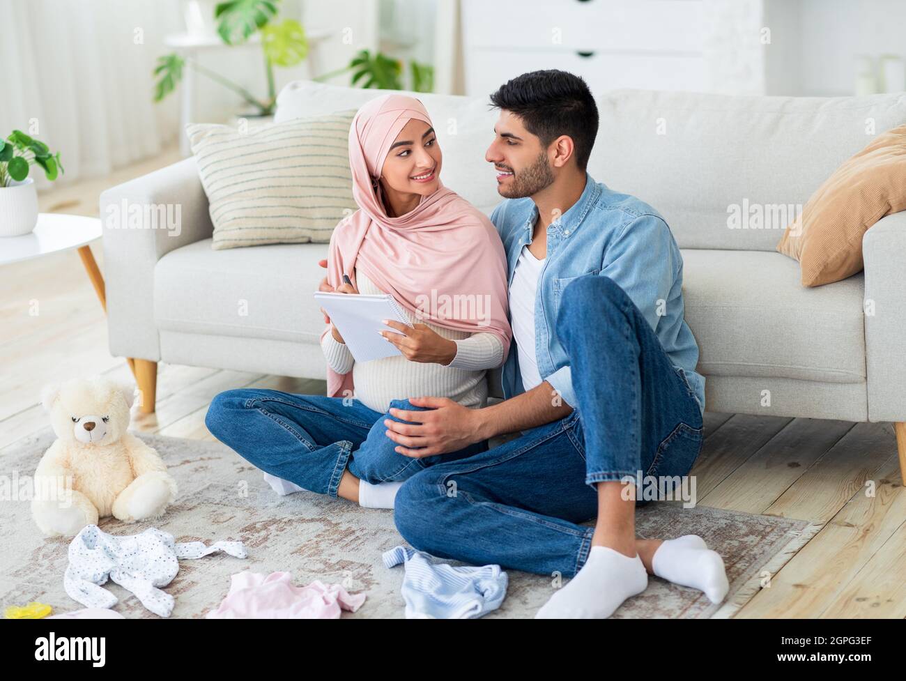 Glücklich verheiratet schwanger arabischen Ehegatten machen Checkliste von Babykleidung und Notizen von Kindersachen für die Geburt Zentrum Stockfoto