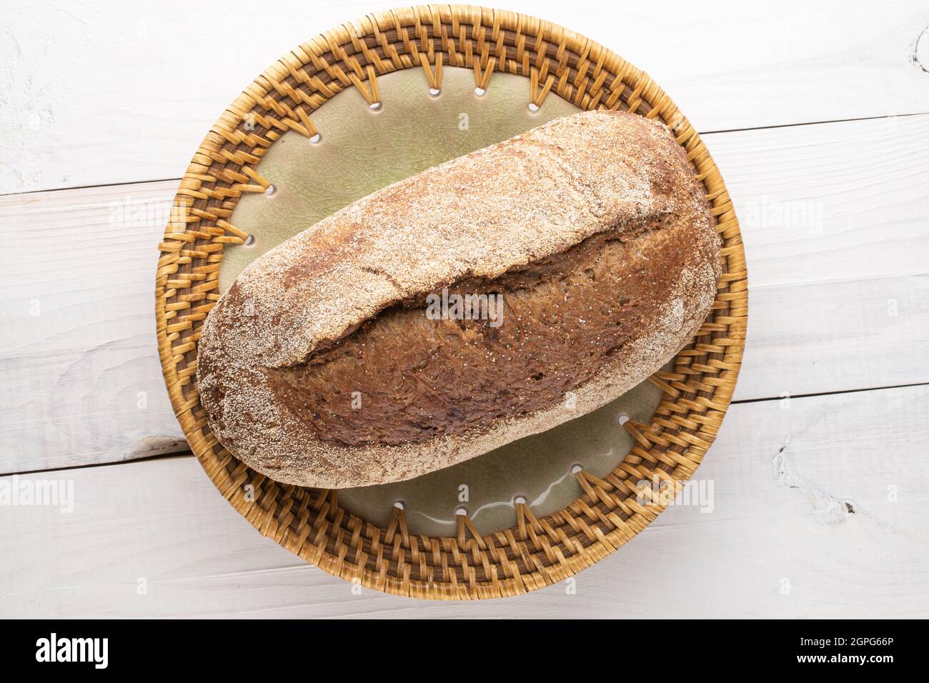 Ein Laib frisch gebackenes griechisches Brot in einer Keramikschale, Nahaufnahme, auf einem Holztisch, Draufsicht. Stockfoto
