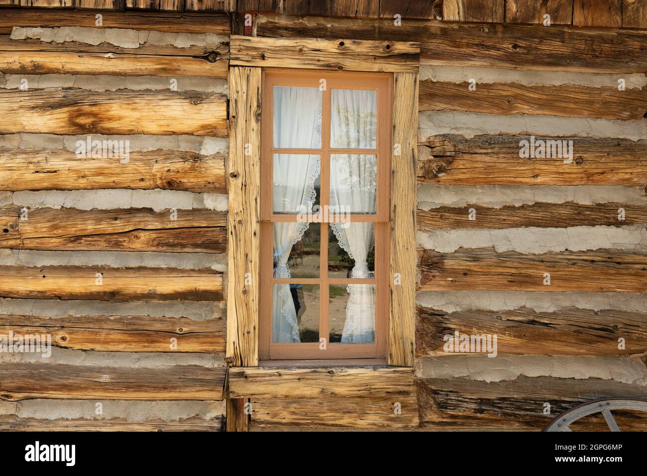 Altes verwittertes Holzfenster mit Vorhang in rustikaler Blockhütte Stockfoto