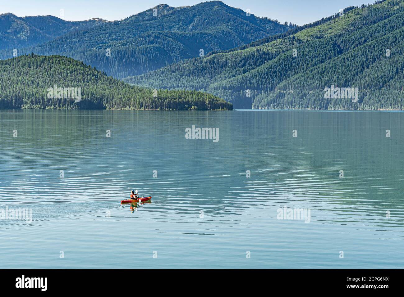 Frau, die alleine auf einem wunderschönen See mit Bergen Kajak gefahren ist Stockfoto