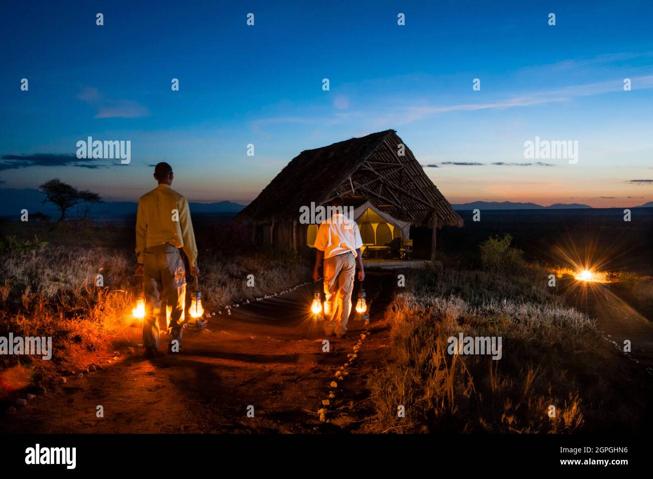 Kenia, Taita Hills, Lualenyi Ranch, Lualenyi Camp, Personal mit Lampen bei Sonnenuntergang Stockfoto