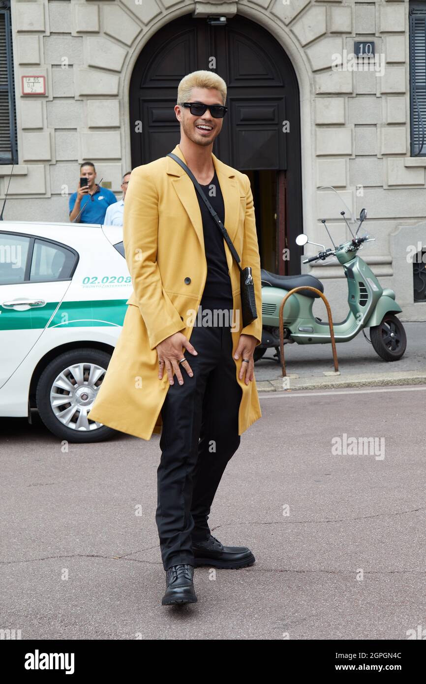 MAILAND, ITALIEN - 25. SEPTEMBER 2021: Ross Butler lächelt mit gelbem Mantel und schwarzer Sonnenbrille vor Salvatore Ferragamo Fashion Show, Milan Fashion We Stockfoto