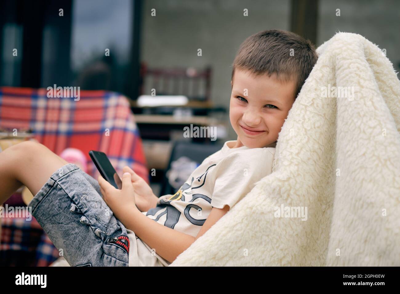 Porträt eines süßen glücklichen kaukasischen Jugendlichen Jungen mit einem Smartphone in der Hand und Blick auf die Kamera Stockfoto