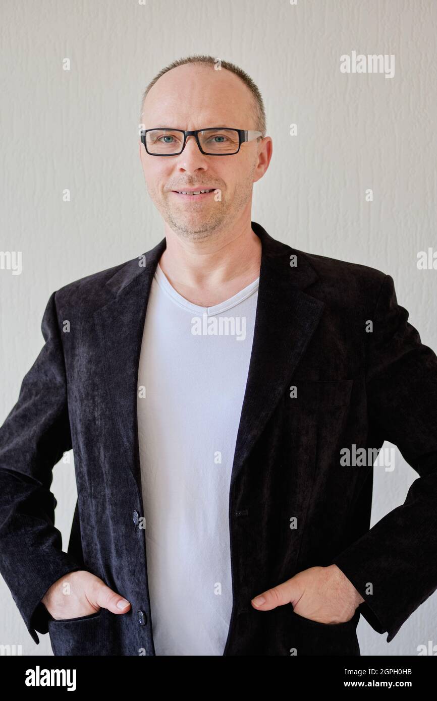 Vorderansicht Porträt eines Mannes in einer schwarzen Jacke auf weißem Hintergrund. Schöner reifer Mann mit schwarzer Brille schaut direkt in die Kamera Stockfoto